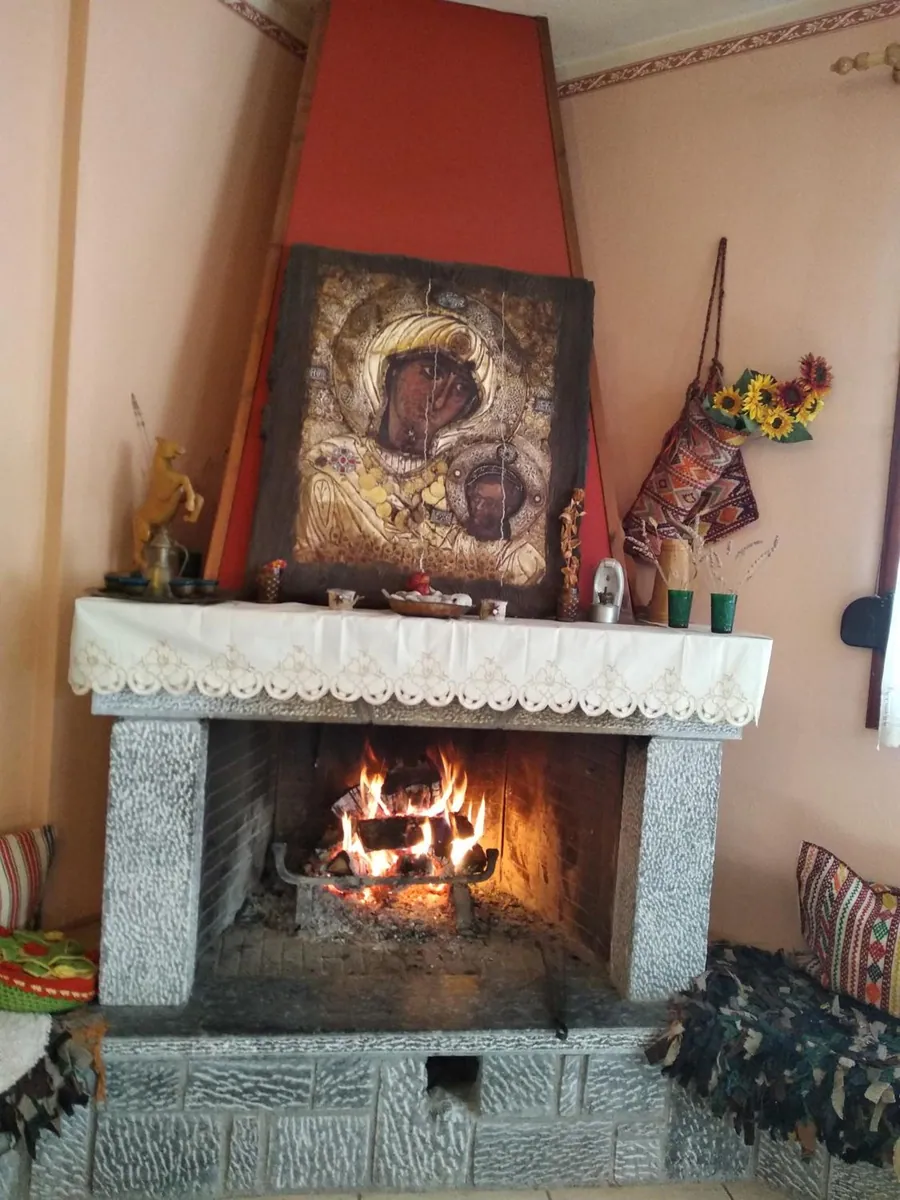 Το τζάκι της σάλας αναμμένο, με μια παλιά εικόνα από πάνω